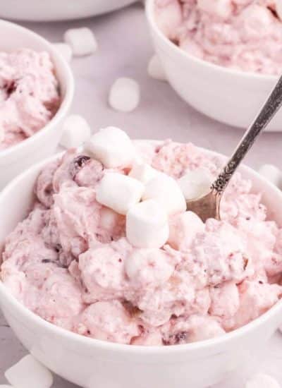 A bowl of strawberry ice cream with marshmallows in it.
