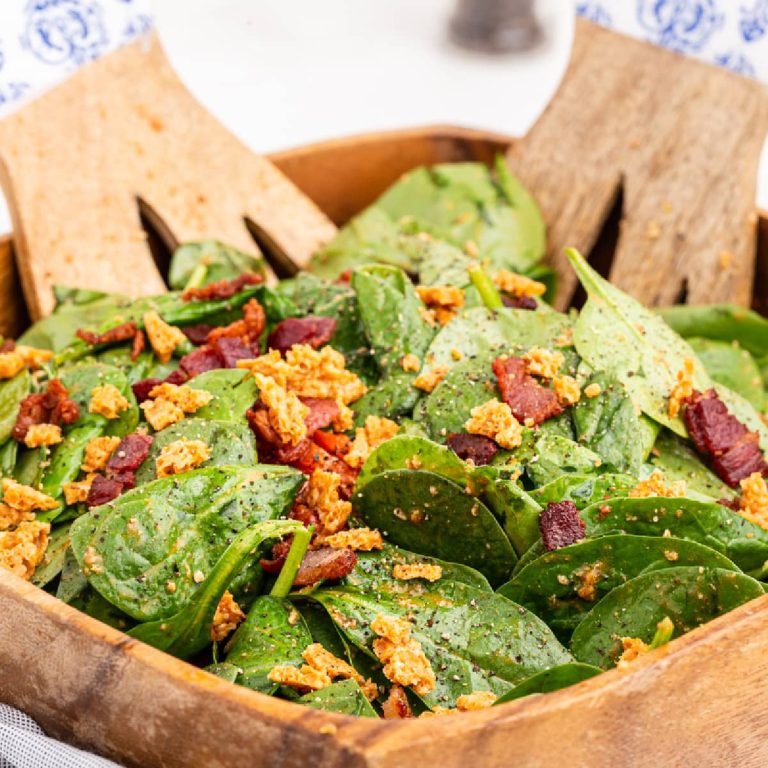 Spinach salad with bacon in a wooden bowl.