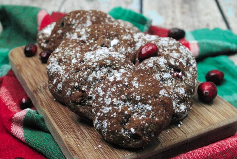 Cranberry cookies with powdered sugar on a wooden cutting board.