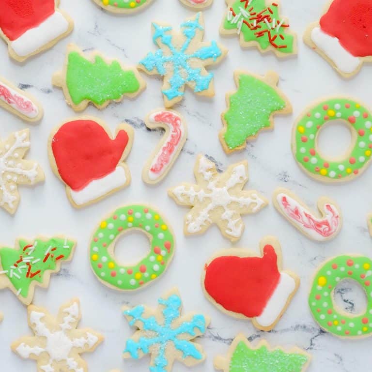 A plate of decorated christmas cookies on a marble table.