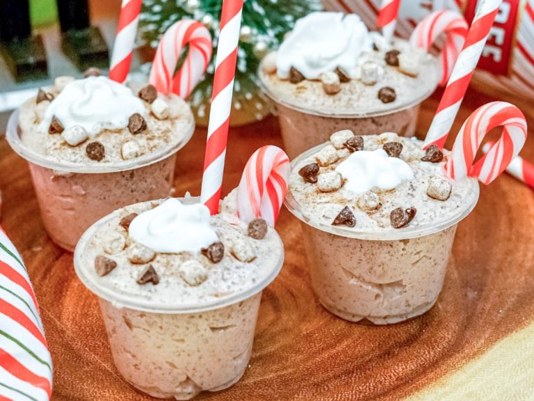 Four small cups with candy canes and whipped cream.