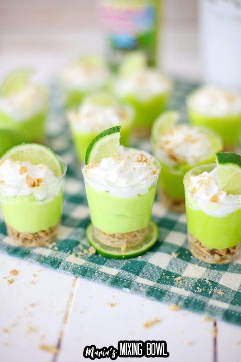 Lime mousse cups with whipped cream on a checkered tablecloth.