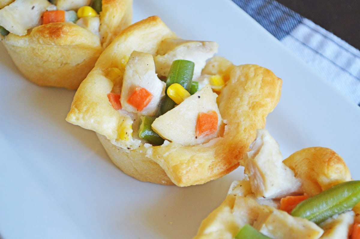close up of mini chicken pot pie showing chicken and vegetables in puffed pastry