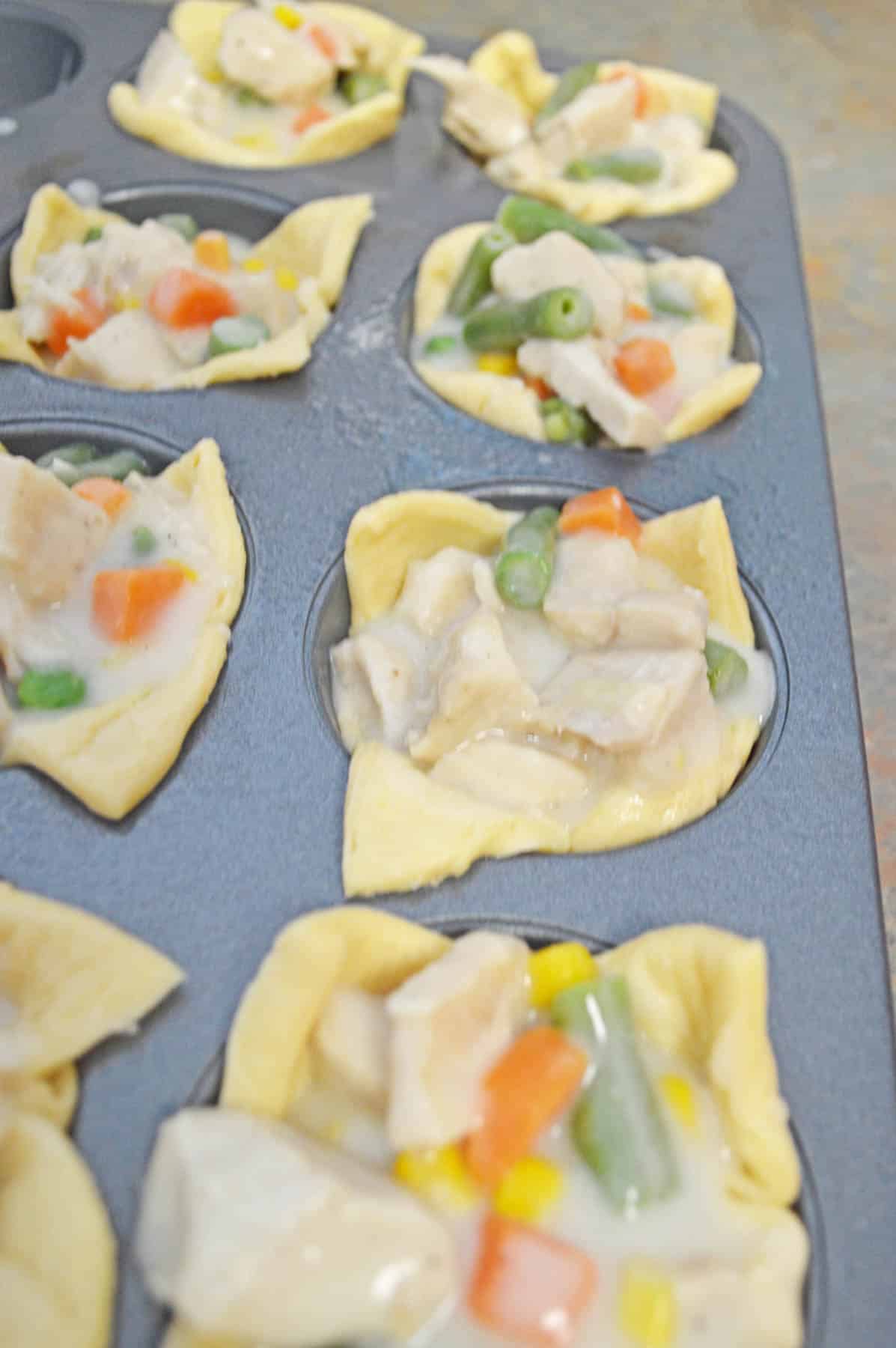 raw puffed pastry in muffin tins with chicken pot pie mixture