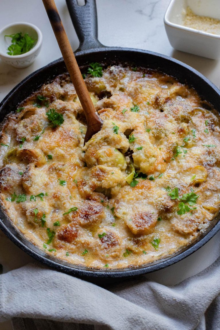 A skillet filled with a cheesy dish and a wooden spoon.