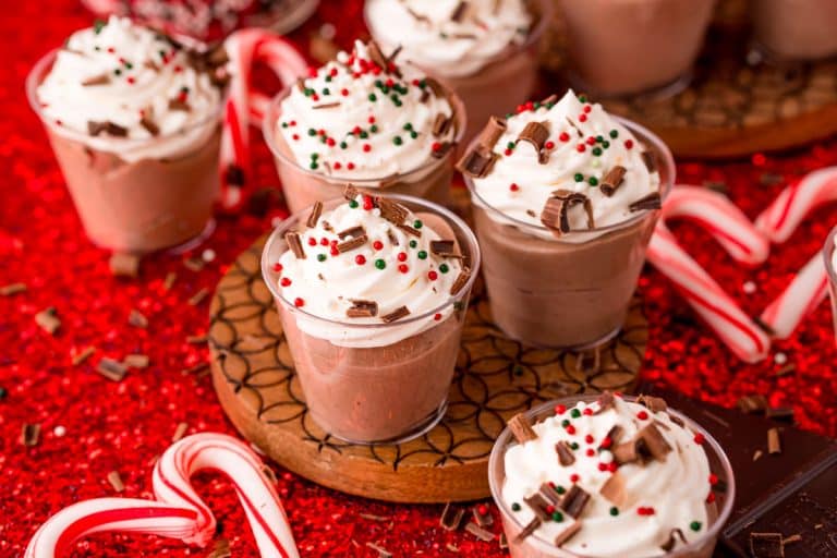 Small cups of hot chocolate with whipped cream and candy canes.