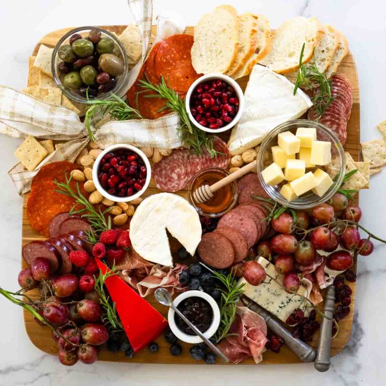 A wooden board with a variety of meats and cheeses.