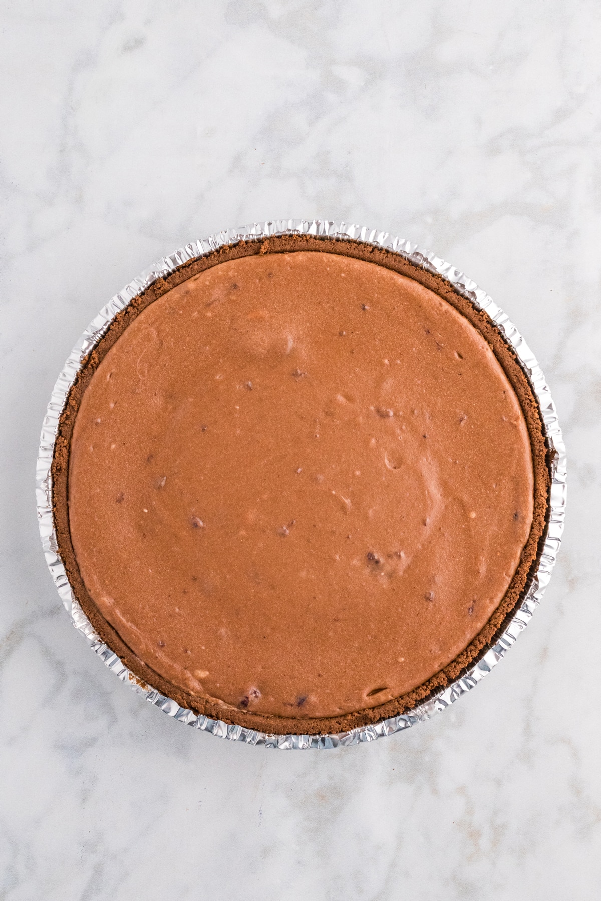 Another process in preparing Chocolate Cherry Cheesecake is to pour the cheesecake filling into the premade chocolate crust, spreading it evenly.