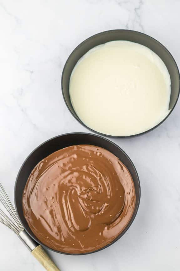 Two bowls of chocolate ganache and a whisk.