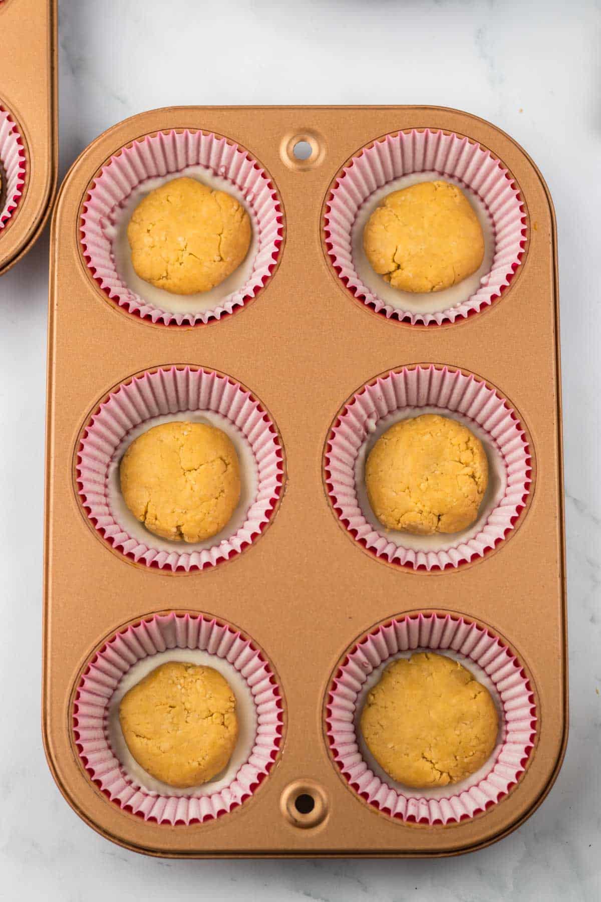 A muffin tin with peanut butter filling in it.