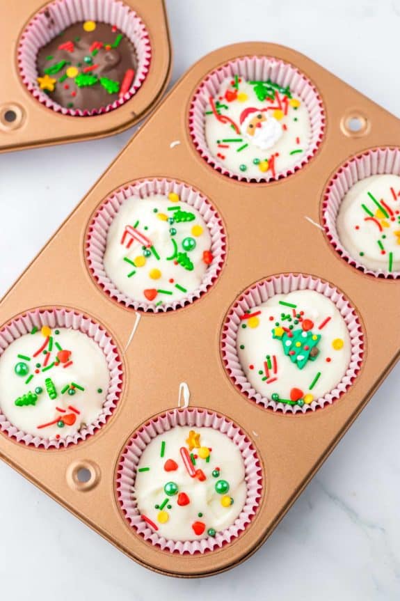 Christmas white chocolate peanut butter cups in a muffin tin with sprinkles.