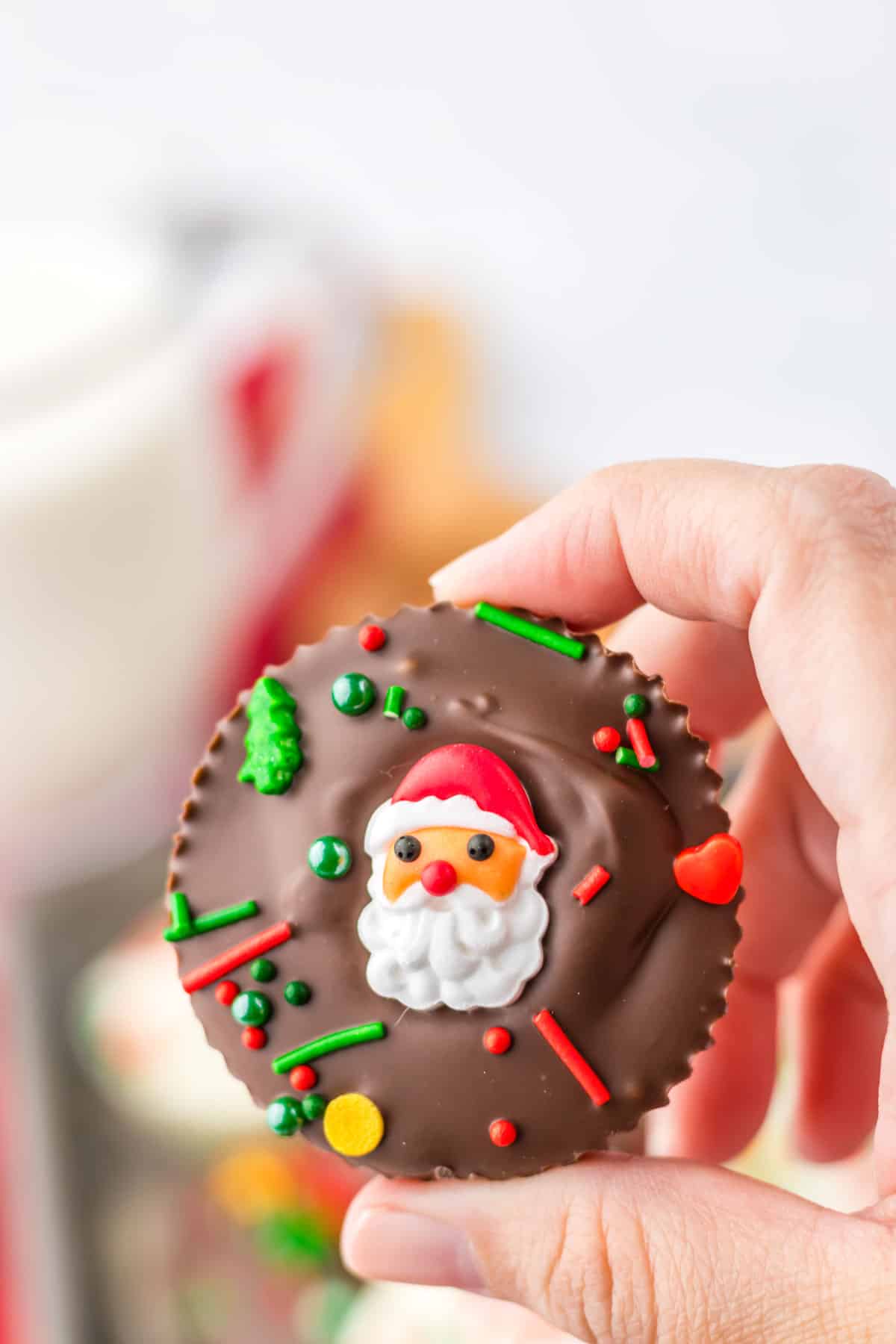 A person holding a chocolate covered santa claus peanut butter cup