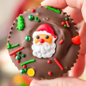 A person holding up a chocolate covered santa claus cookie.