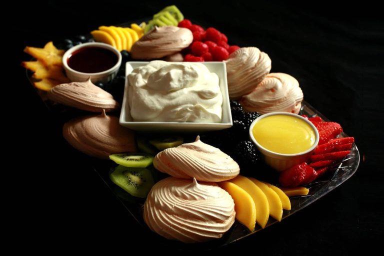 A tray with fruit and desserts on it.