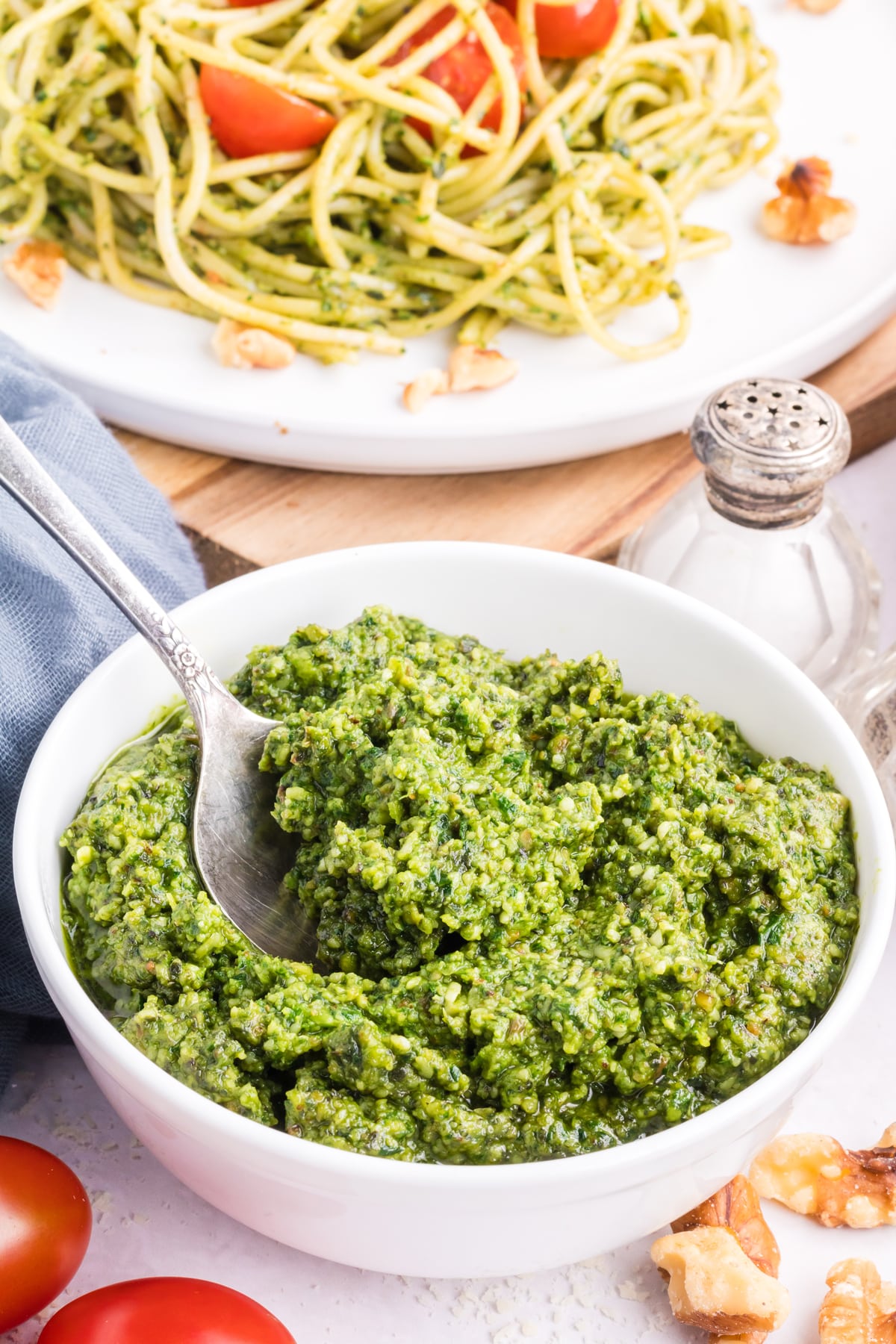 A bowl of pesto with tomatoes and basil.