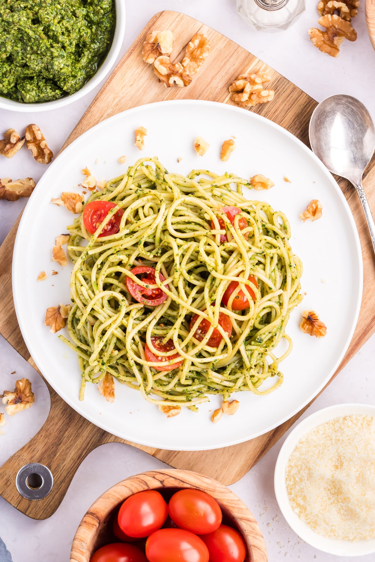 A plate of homemade pesto pasta with tomatoes and walnuts.