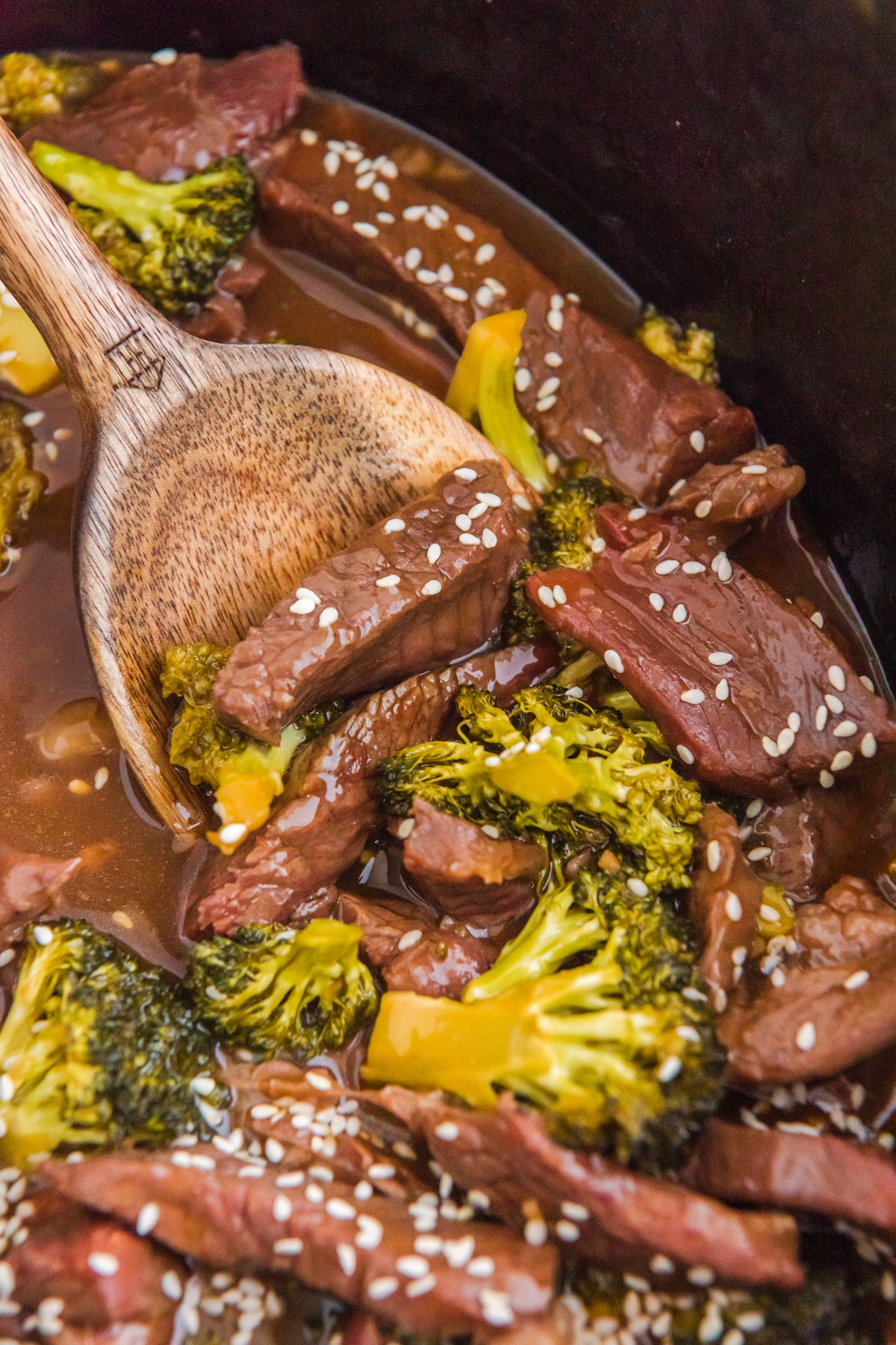 Slow Cooker Beef and Broccoli in a pot with a wooden spoon.