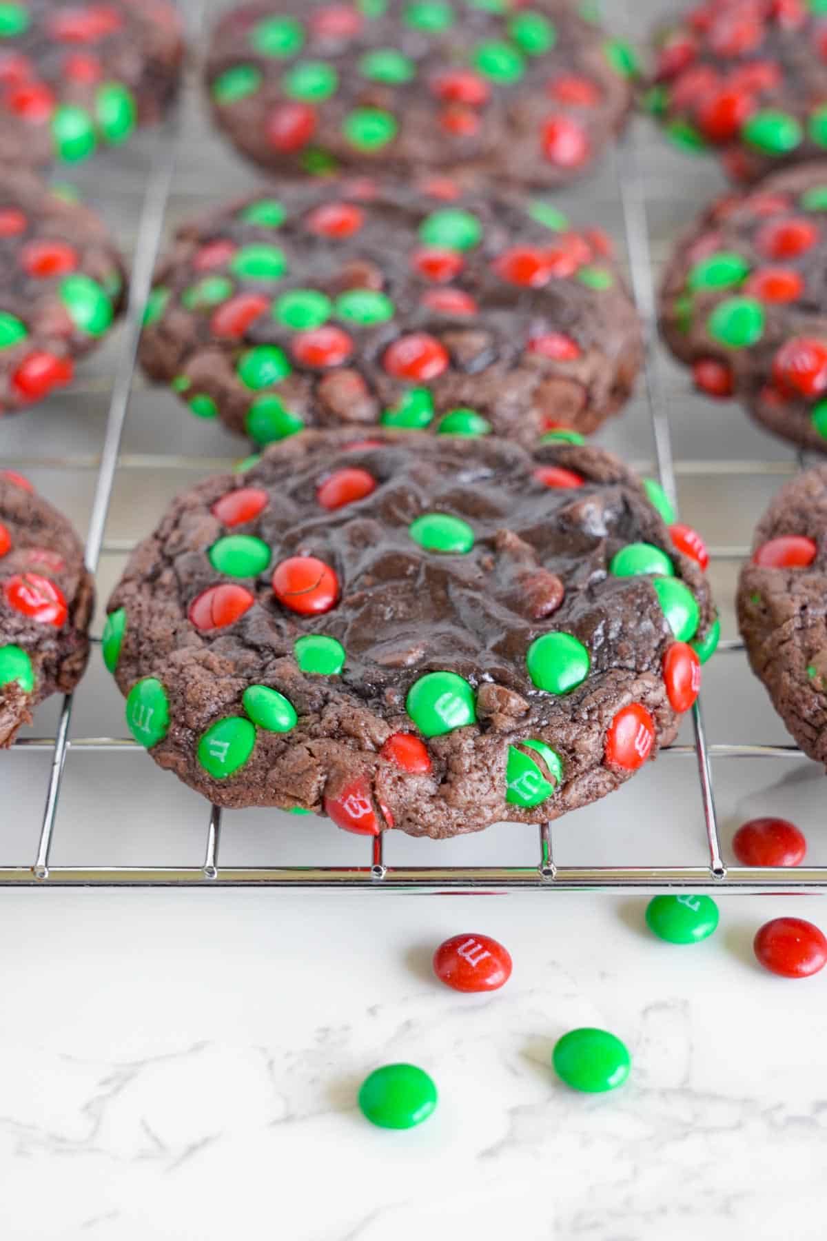 Chocolate cookies with green and red sprinkles on a cooling rack.