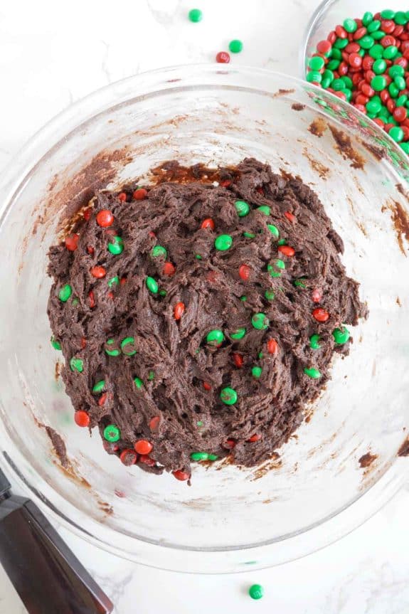 Chocolate cookie dough in a bowl with green and red sprinkles.