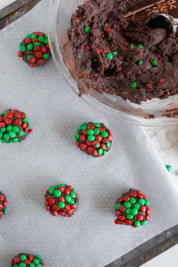 Chocolate m&m cookies on a baking sheet with green and red m&ms.