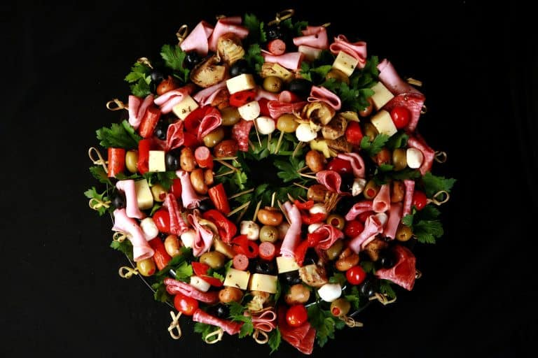 A circular arrangement of meats and vegetables on a black background.