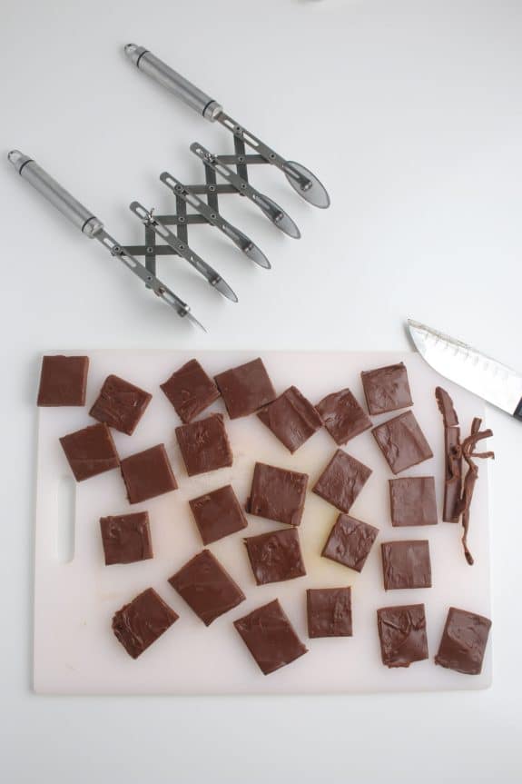 A cutting board with chocolate pieces and a knife.