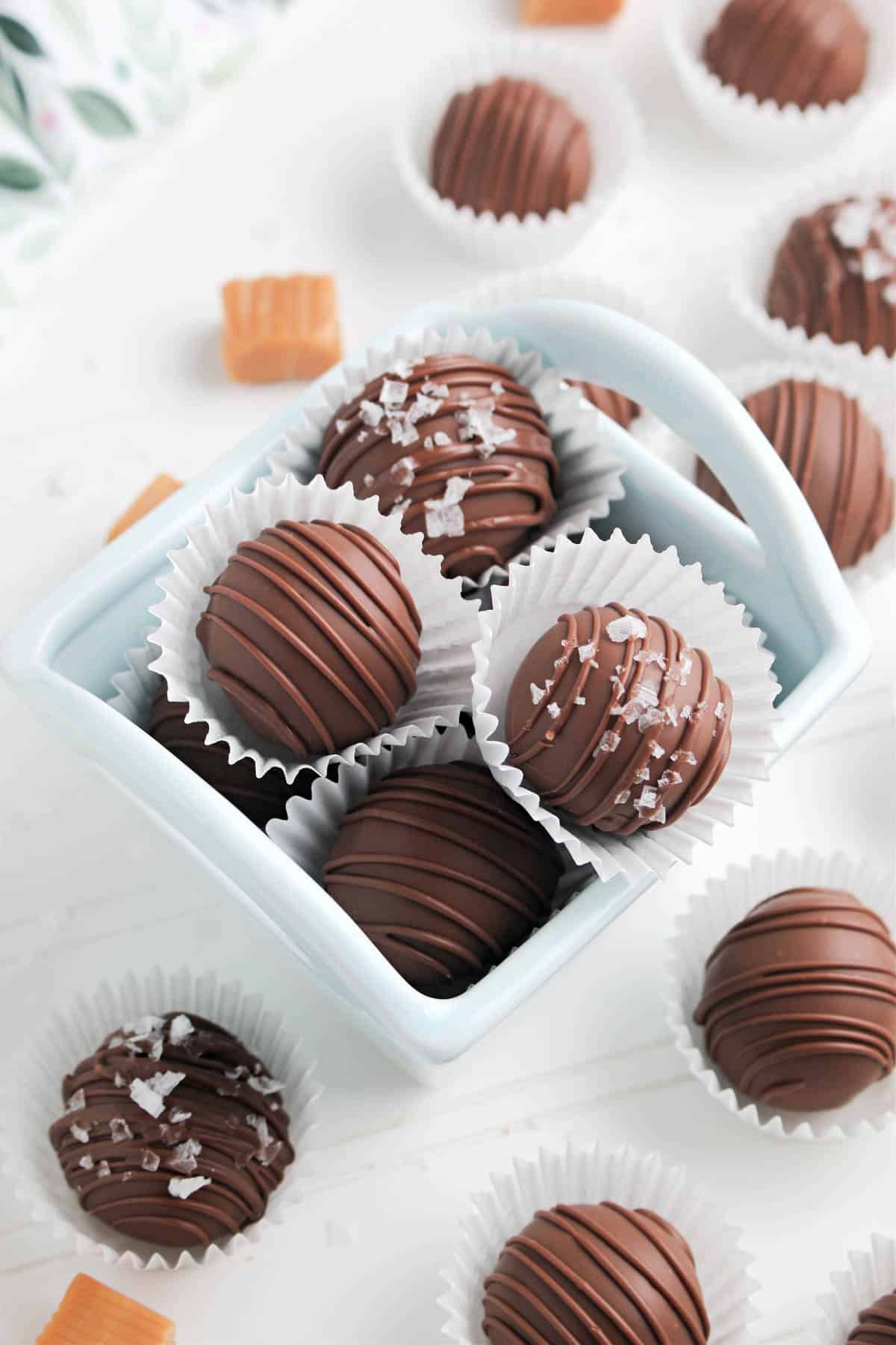 Chocolate truffles in a blue bowl on a white background.