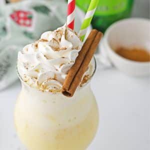 Eggnog floats with whipped cream and cinnamon sticks.