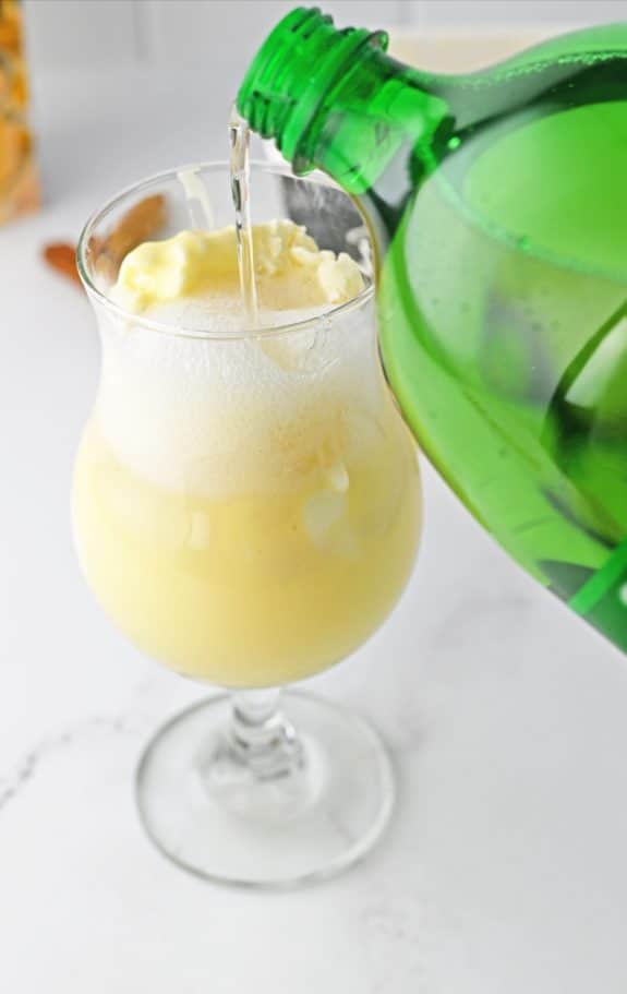 Glass with vanilla ice cream and soda being poured on top