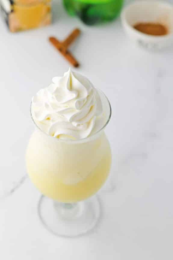 A glass of eggnog float with whipped cream and cinnamon.