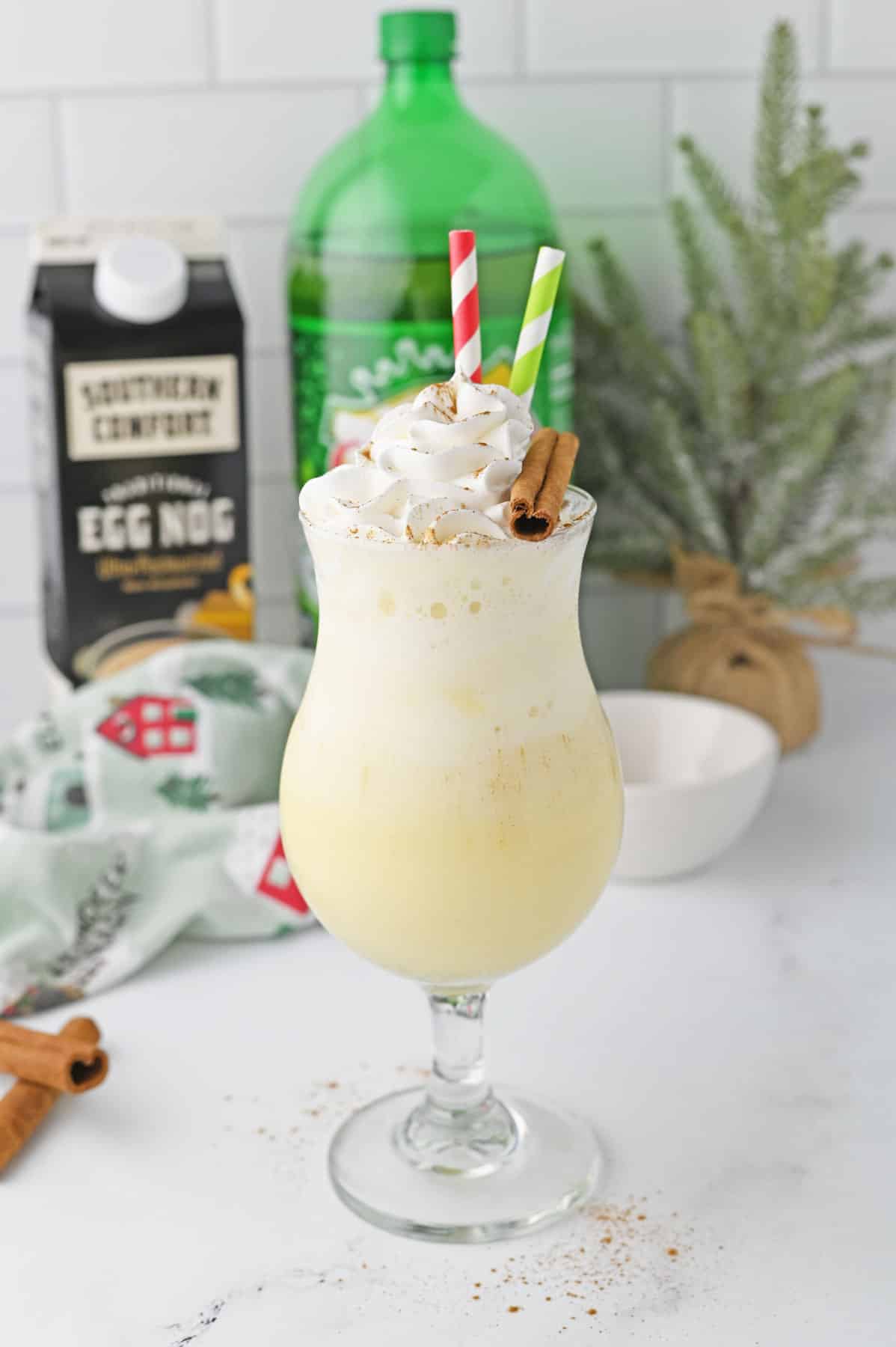 Eggnog float in a glass with whipped cream and cinnamon sticks.