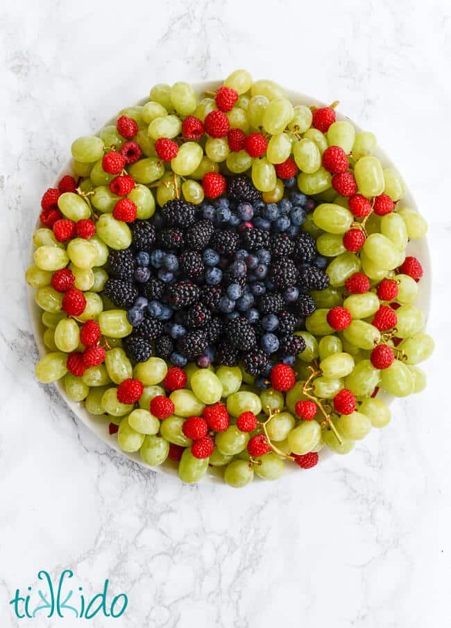A plate of grapes and raspberries.