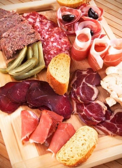 How to build a charcuterie board with a variety of meats on a wooden cutting board.