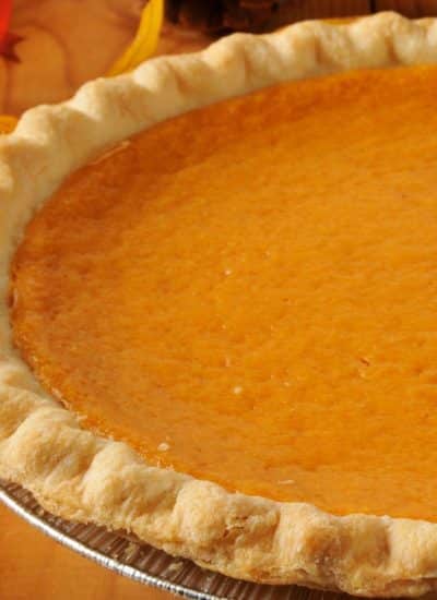 A pumpkin pie, still warm from the oven, is sitting on a rustic wooden table.