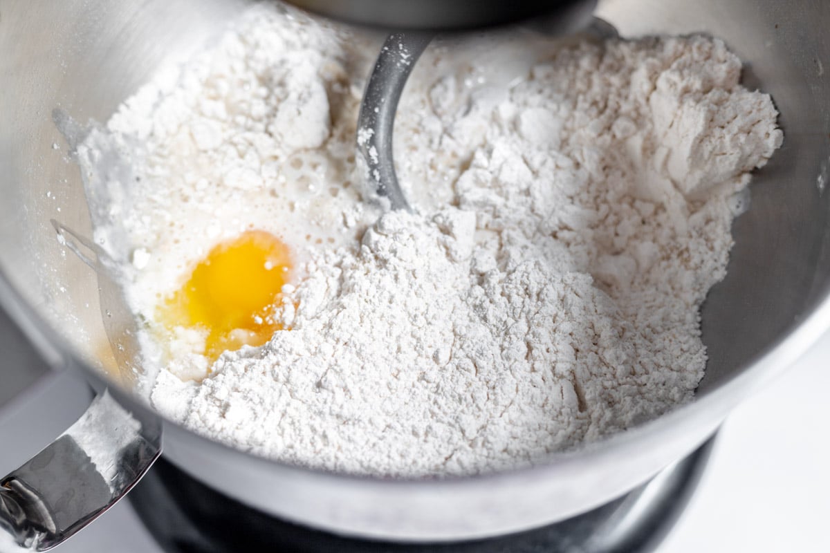 A bowl of flour and an egg in a food processor.