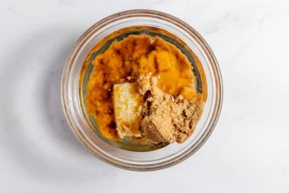 A glass bowl filled with mashed bananas and peanut butter.