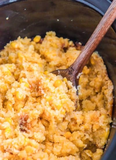 Slow cooker cornbread casserole with a wooden spoon.
