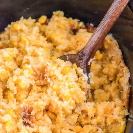 Slow cooker cornbread casserole with a wooden spoon.