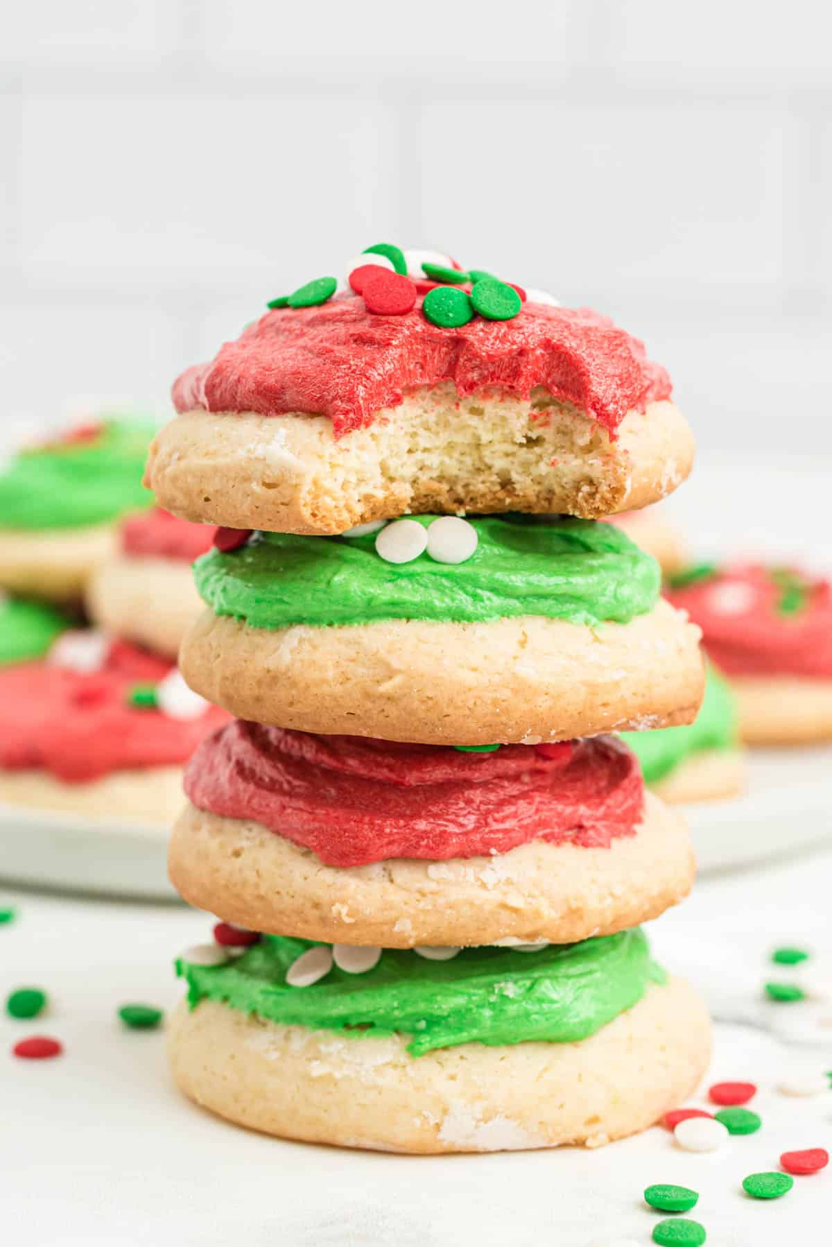 A stack of cookies with green frosting and red sprinkles.
