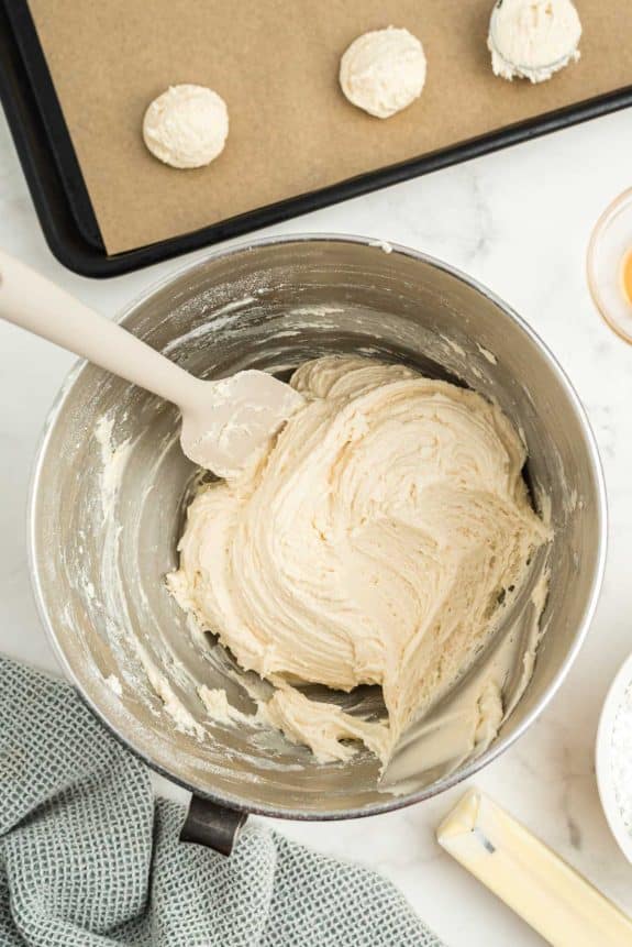 A bowl of dough with a spoon next to it.