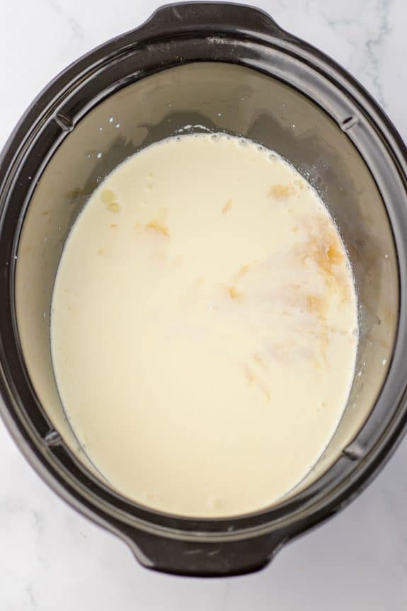 A crock pot filled with a milk.