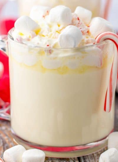 A cup of slow cooker white hot chocolate with marshmallows and candy canes.