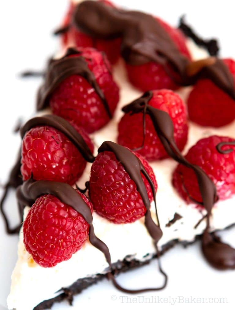 A slice of pie with chocolate and raspberries on top.