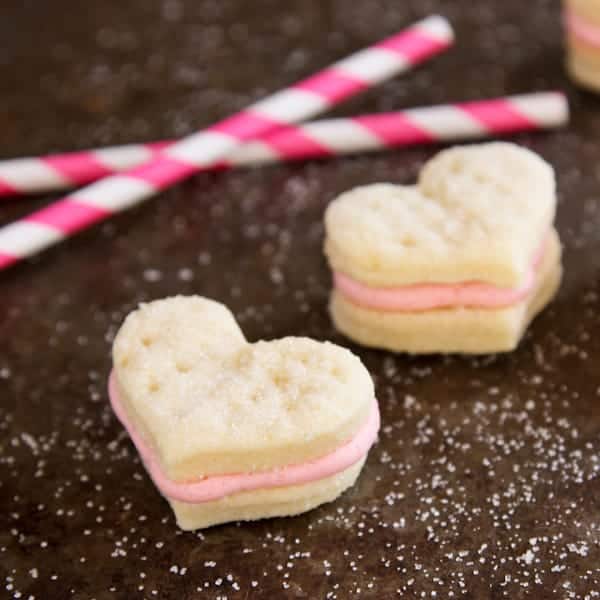 Valentine's day heart cookies on a table with pink and white straws.