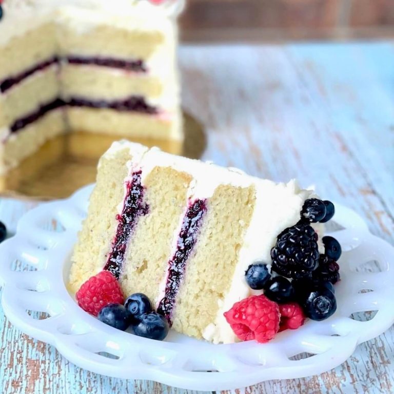 A slice of cake with berries and cream on a plate.
