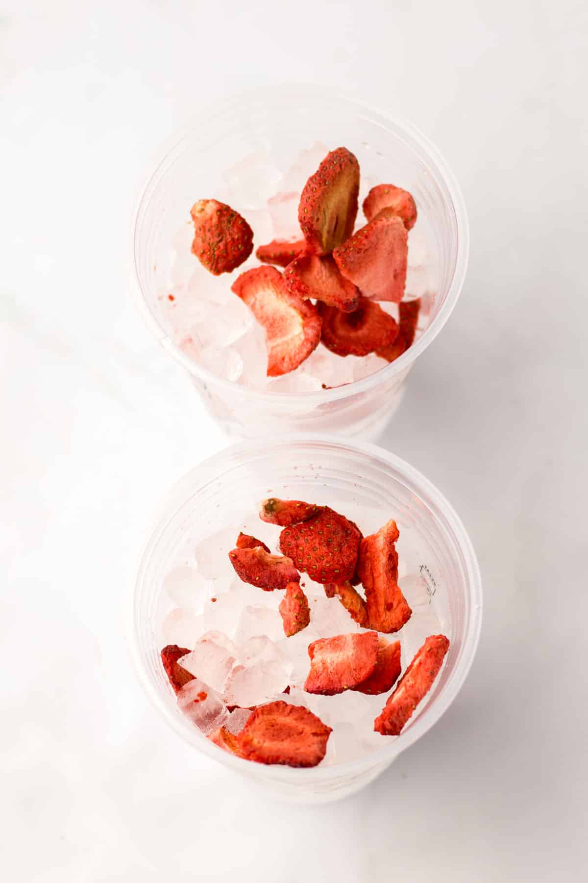 First process in preparing Copycat Starbucks Pink Drink is to add frozen dried strawberries in a cup of ice.