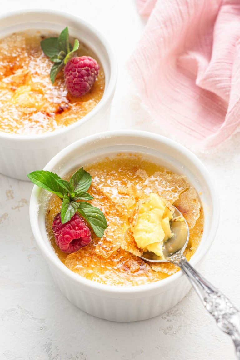 Two bowls of creme brulee with raspberries.