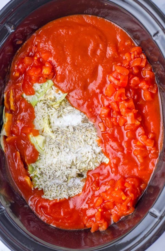 A crock pot filled with tomato sauce and vegetables.