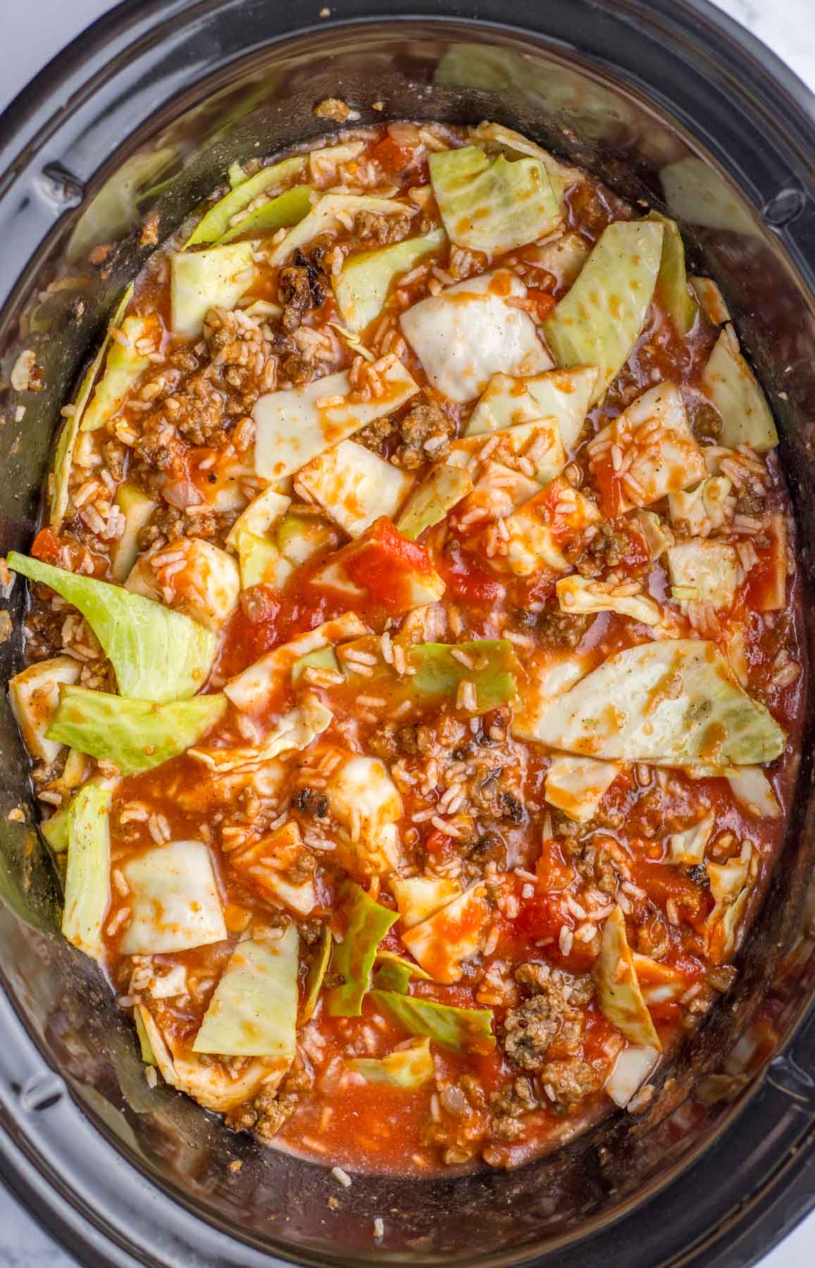 A crock pot filled with cabbage and meat.
