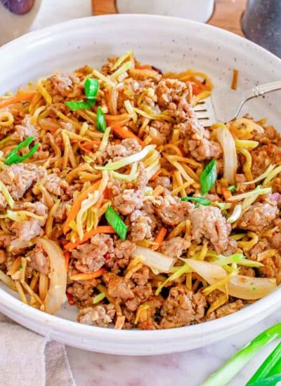 An egg roll in a bowl with meat, vegetables, and noodles.